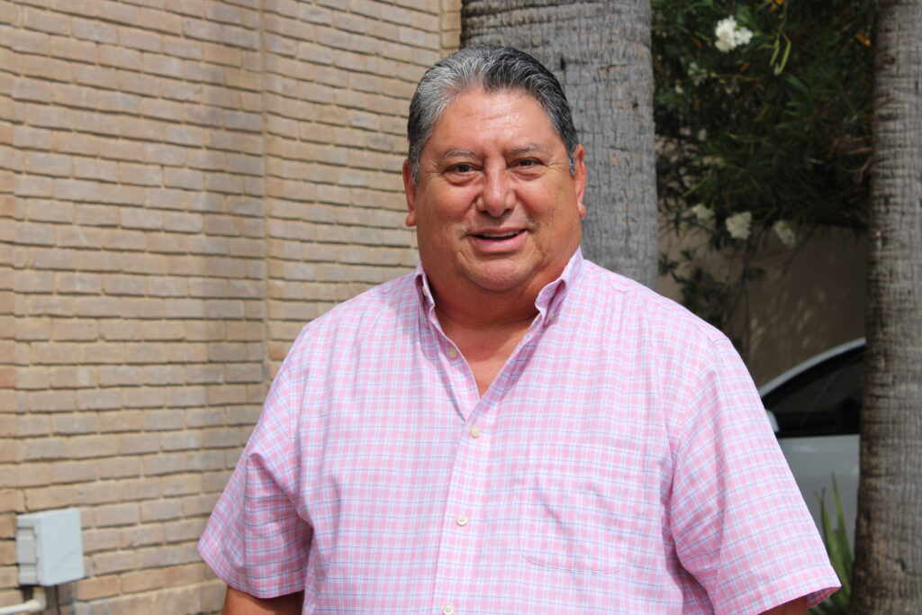David García, president of the Matamoros Business Coordinating Council, standing outside in a light pink plaid shirt.