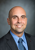 Texas State Rep. Armando Martinez in a black suit with a blue shirt and blue tie.