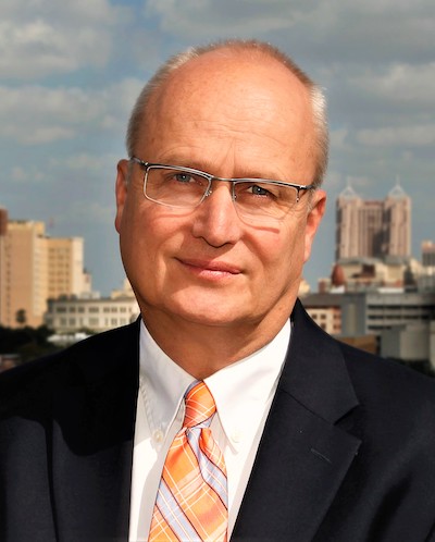 Lloyd Potter wearing a black suit and an orange tie. 