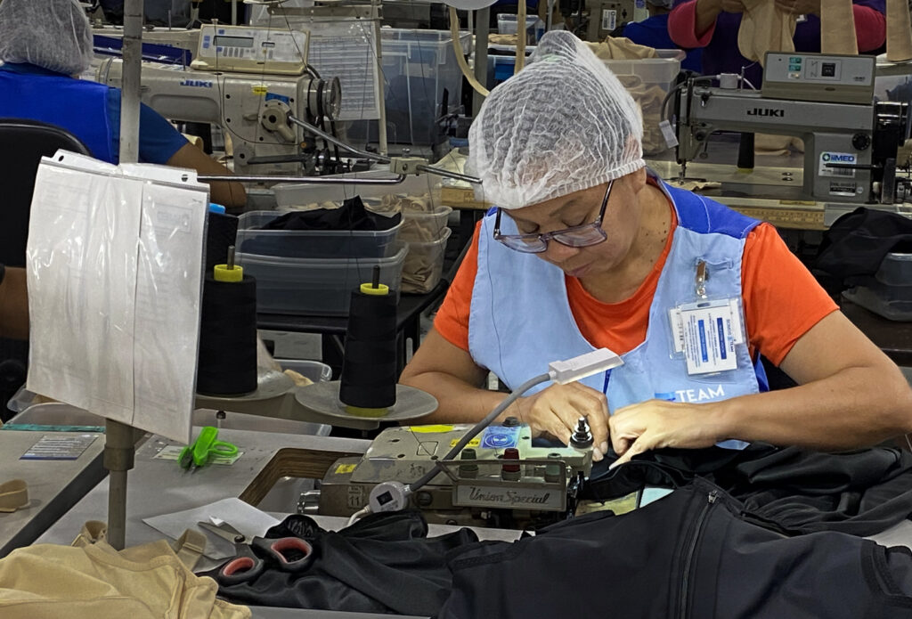 A worker at a sewing machine stitches garments inside a maquiladora in Reynosa, Mexico.