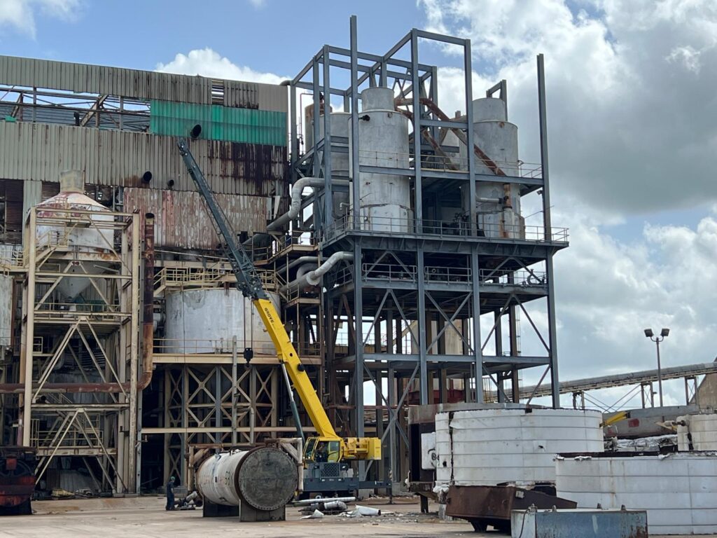 Industrial sugar mill equipment and rusting tanks at the shuttered Santa Rosa facility with a crane on site.