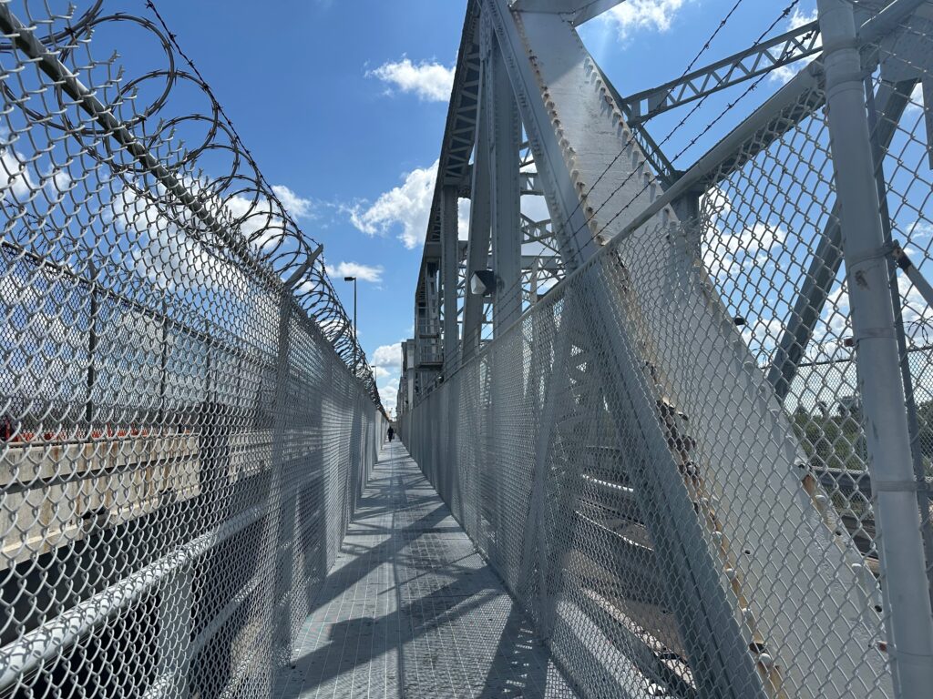Pedestrian path enclosed by fencing along the Brownsville & Matamoros Bridge structure.