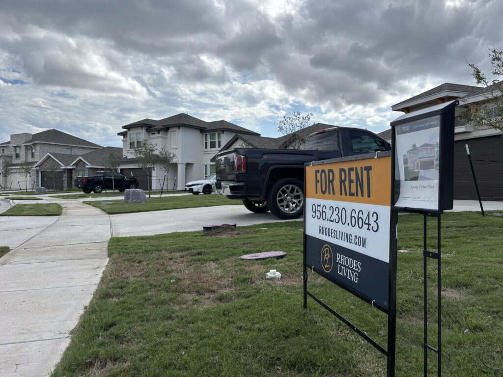 A “For Rent” sign for Rhodes Living displayed in front of newly built two-story homes at Belterra at Tres Lagos in McAllen.