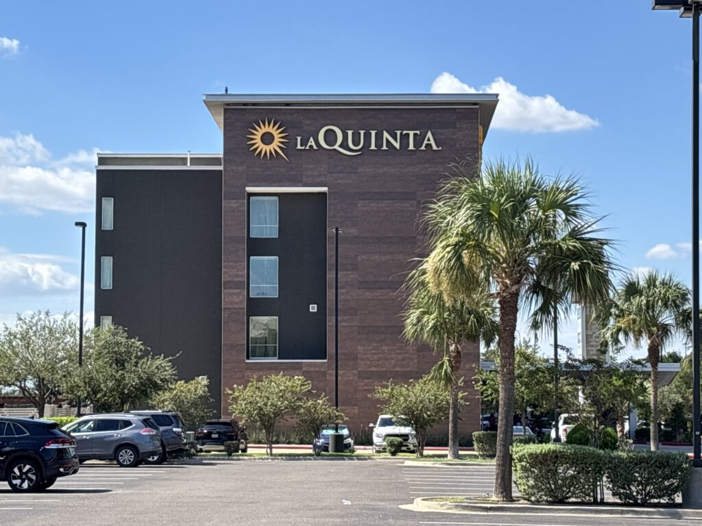 La Quinta hotel in McAllen with palm trees and parked cars in front.
