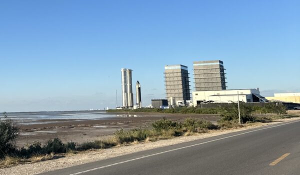 View of the SpaceX Starbase launch and production area near Boca Chica Beach with rocket prototypes and assembly towers visible along the shoreline.
