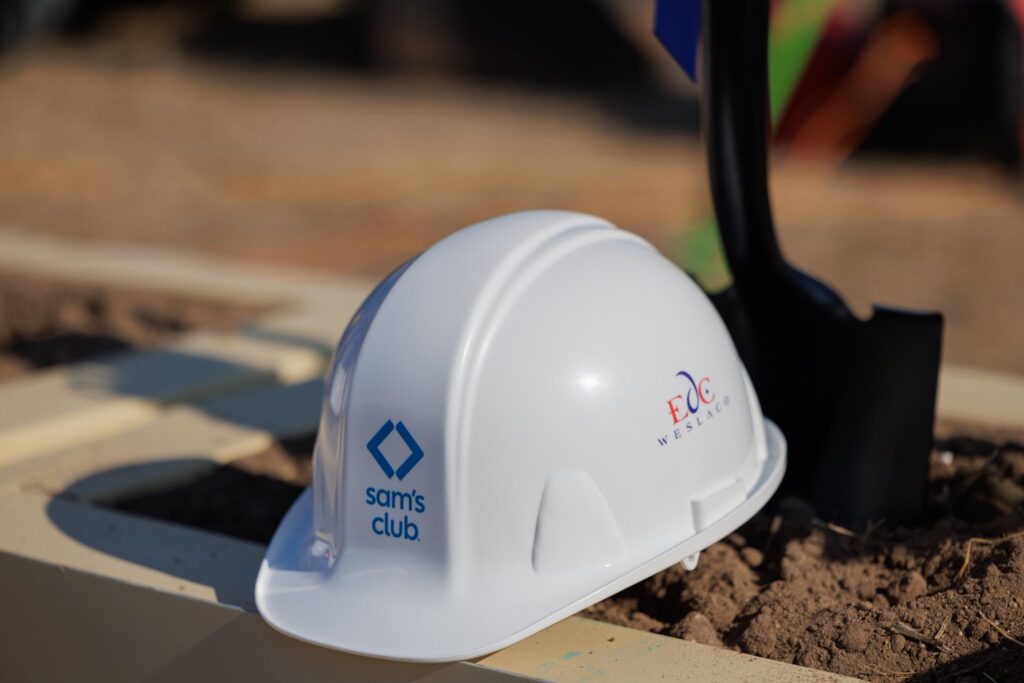 White hard hat with Sam’s Club and Weslaco EDC logos next to a shovel at the groundbreaking site.