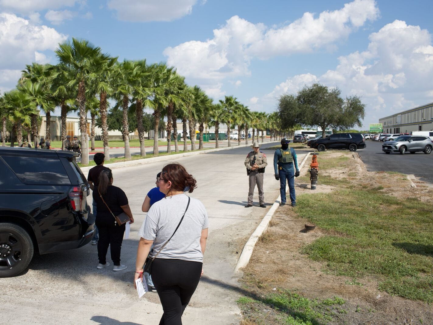 ICE agents and DPS troopers secure the perimeter outside the Tres Dimensiones Ropa Usada warehouse in McAllen on Thursday as onlookers gather nearby. 