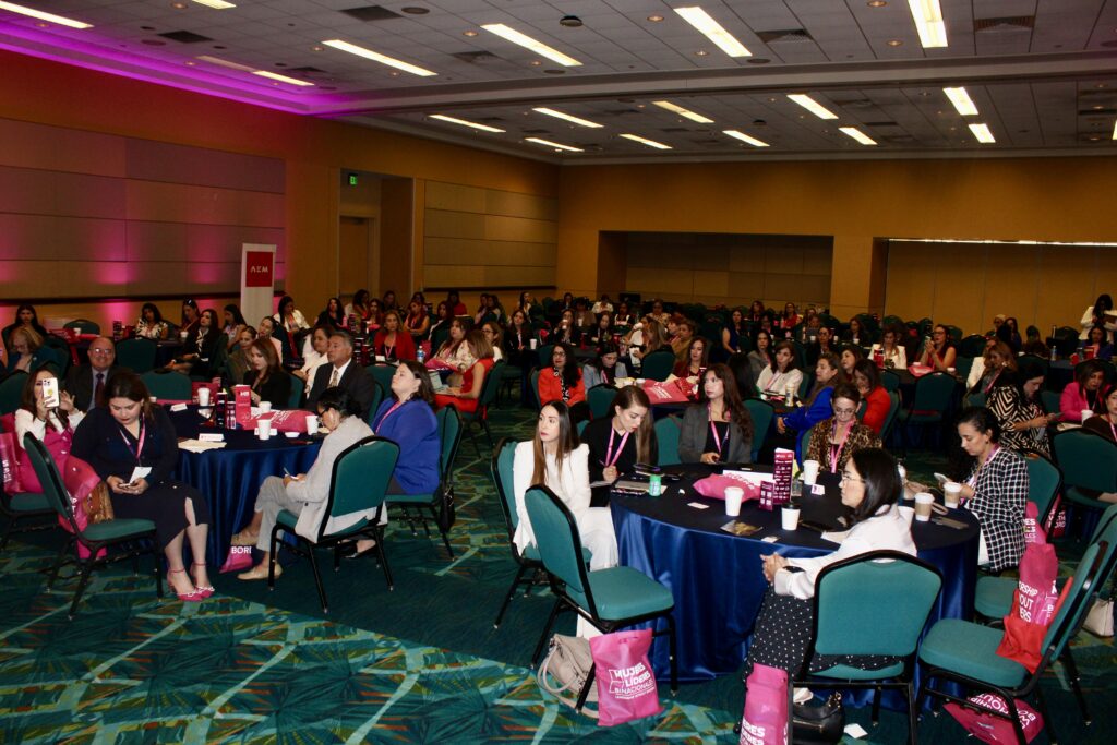 Audience seated at round tables watching presentations during the Mujeres Líderes Binacionales – Leads North America Summit in McAllen.