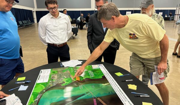 Residents gathered around display boards reviewing TxDOT route maps for the proposed South Padre Island second causeway during the public meeting.