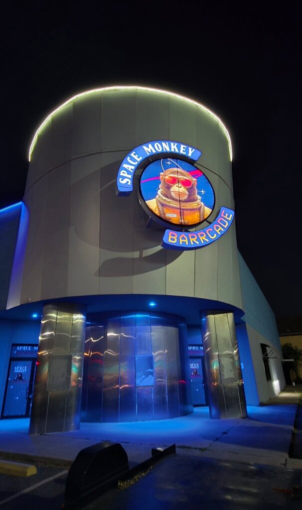 Nighttime view of the Space Monkey Barrcade building with its illuminated circular sign.