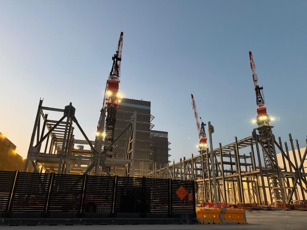 Steel framing and cranes at the SpaceX Gigabay construction site at dusk.