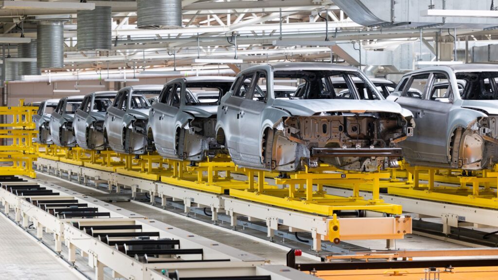 Line of partially assembled car bodies moving through a North American auto manufacturing facility.