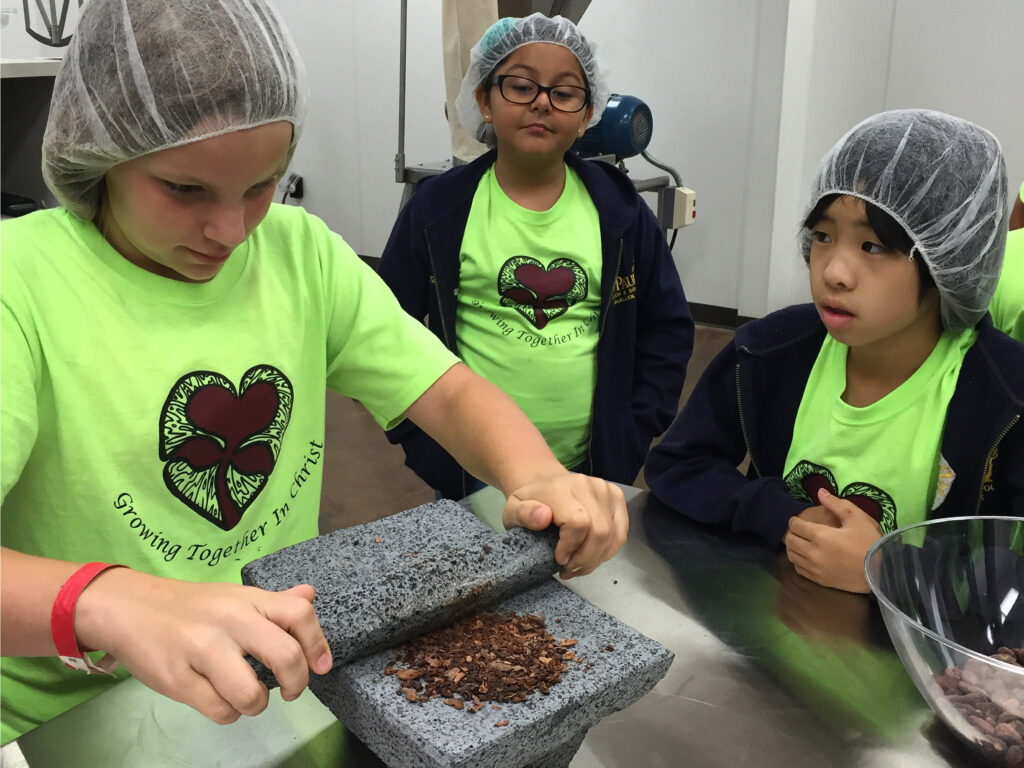 Los niños observan cómo se muele el cacao durante una visita guiada a Mozna Chocolate.