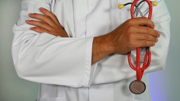 A health care professional wearing a white coat holds a stethoscope, representing rising health insurance costs and coverage decisions in the Rio Grande Valley.