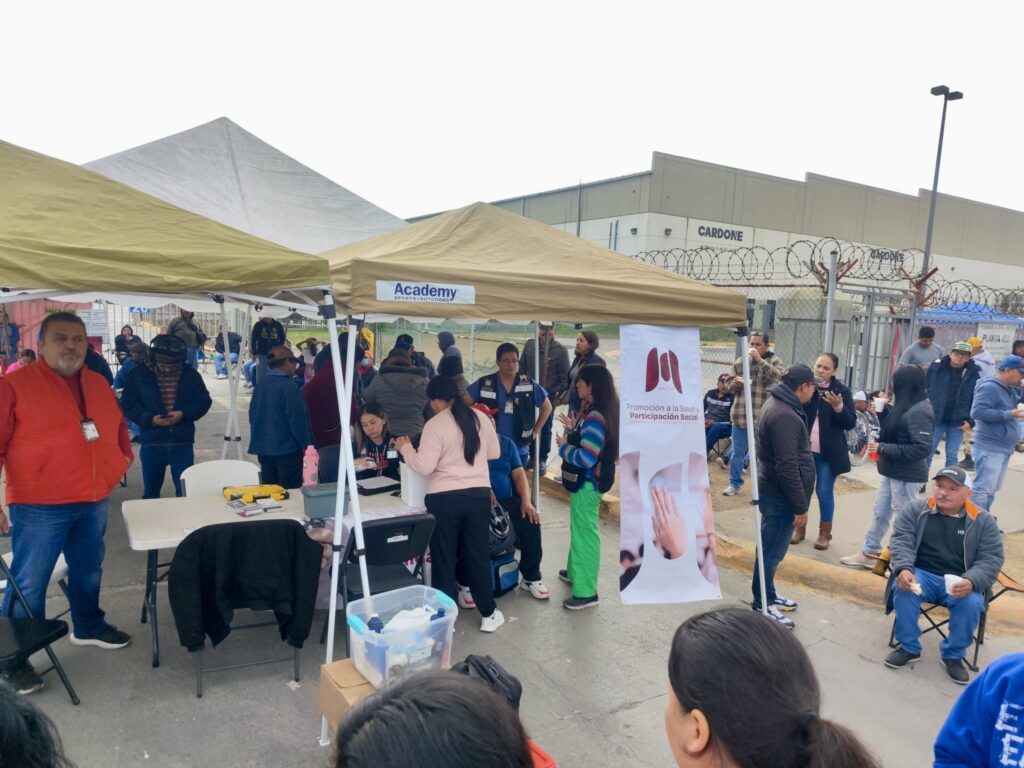 Workers stand and sit under temporary tents outside a Cardone manufacturing plant in Matamoros while staff provide basic medical services and assistance to employees affected by the shutdown.