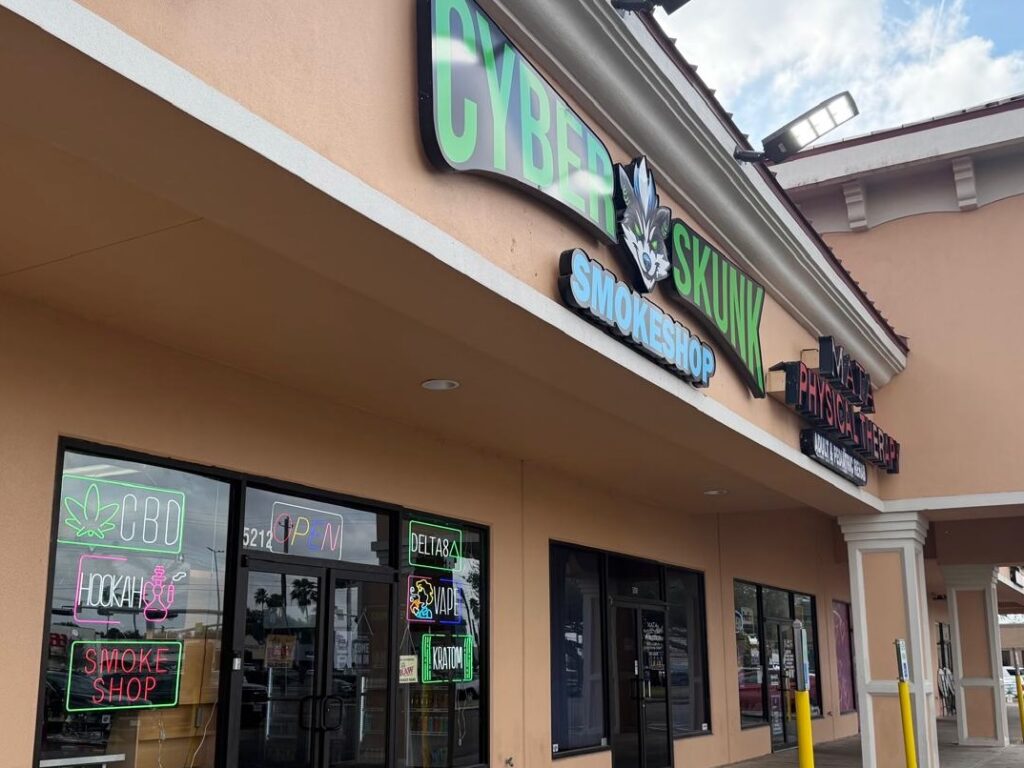 Exterior of Cyberskunk Smokeshop in McAllen with illuminated storefront signage in a strip shopping center.