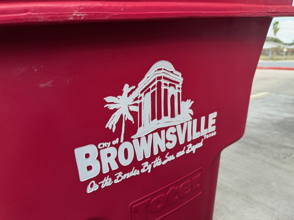 Close-up of a red City of Brownsville curbside recycling bin.