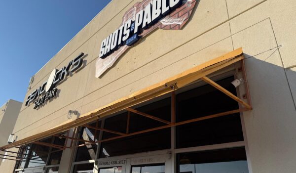 Exterior view of Shots on Pablo and Peacocks Shot Bar signage at a midtown Brownsville plaza along Pablo Kisel Boulevard.