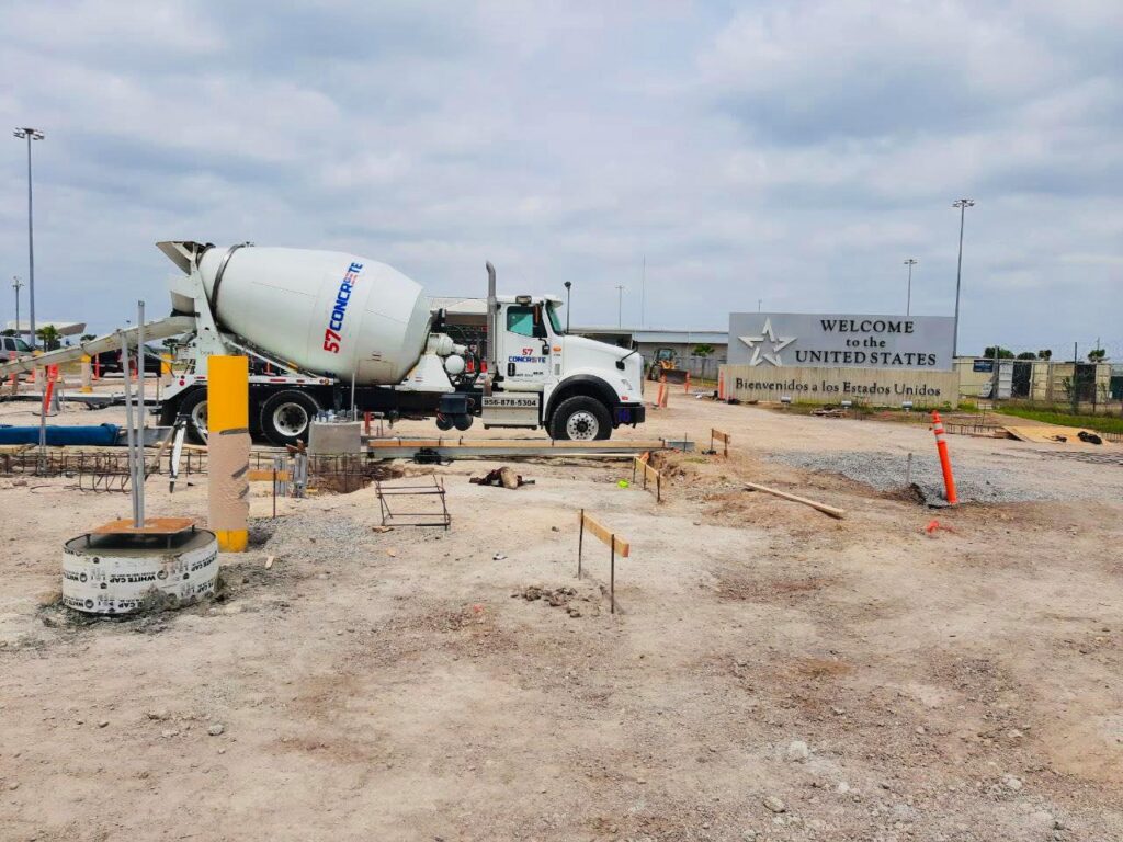 A 57 Concrete mixer truck parked at a construction site near a “Welcome to the United States” sign.