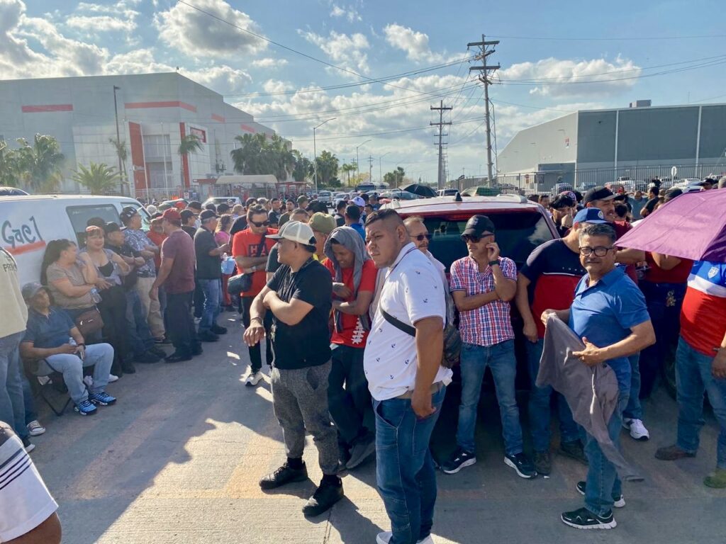 Workers stand near the Tridonex plant entrance as legal actions move forward.