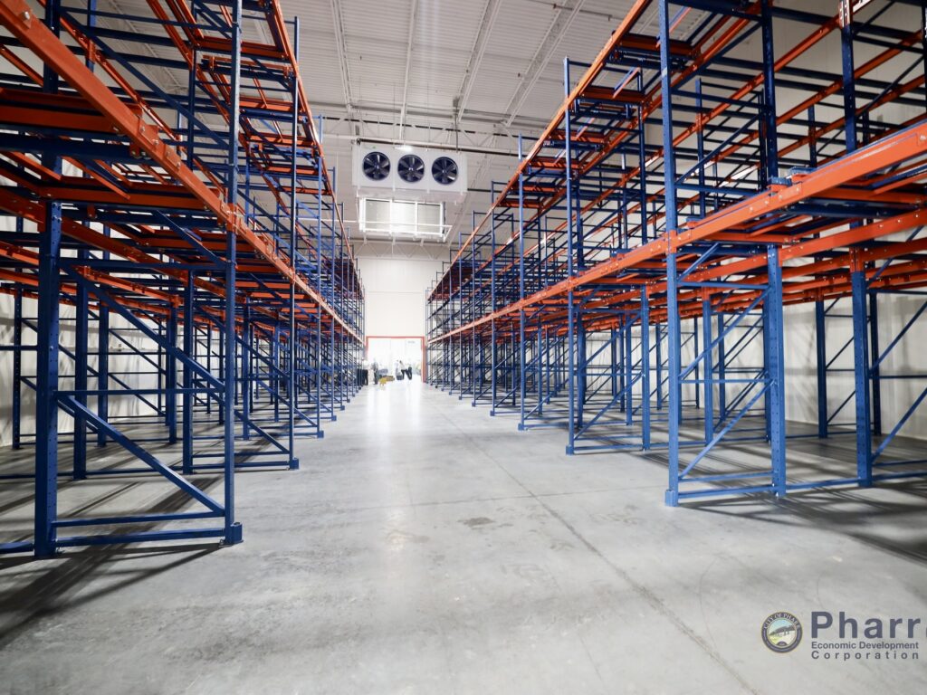Rows of industrial blue and orange storage racks inside the refrigerated warehouse.