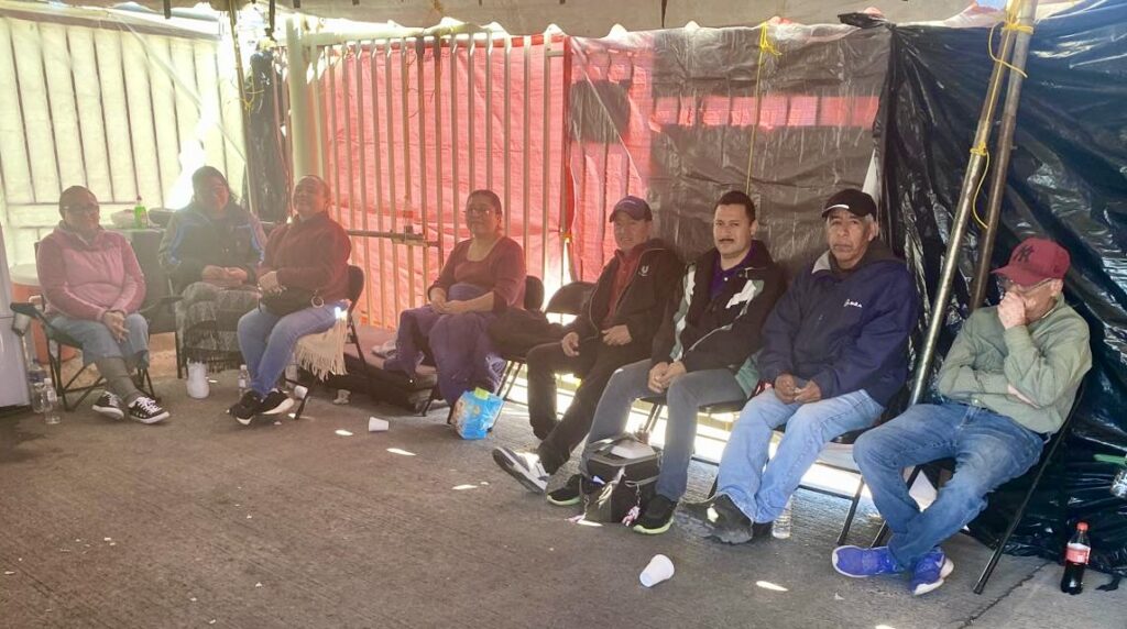 Workers sit inside a tent outside the Tridonex plant in Matamoros during guard shifts.