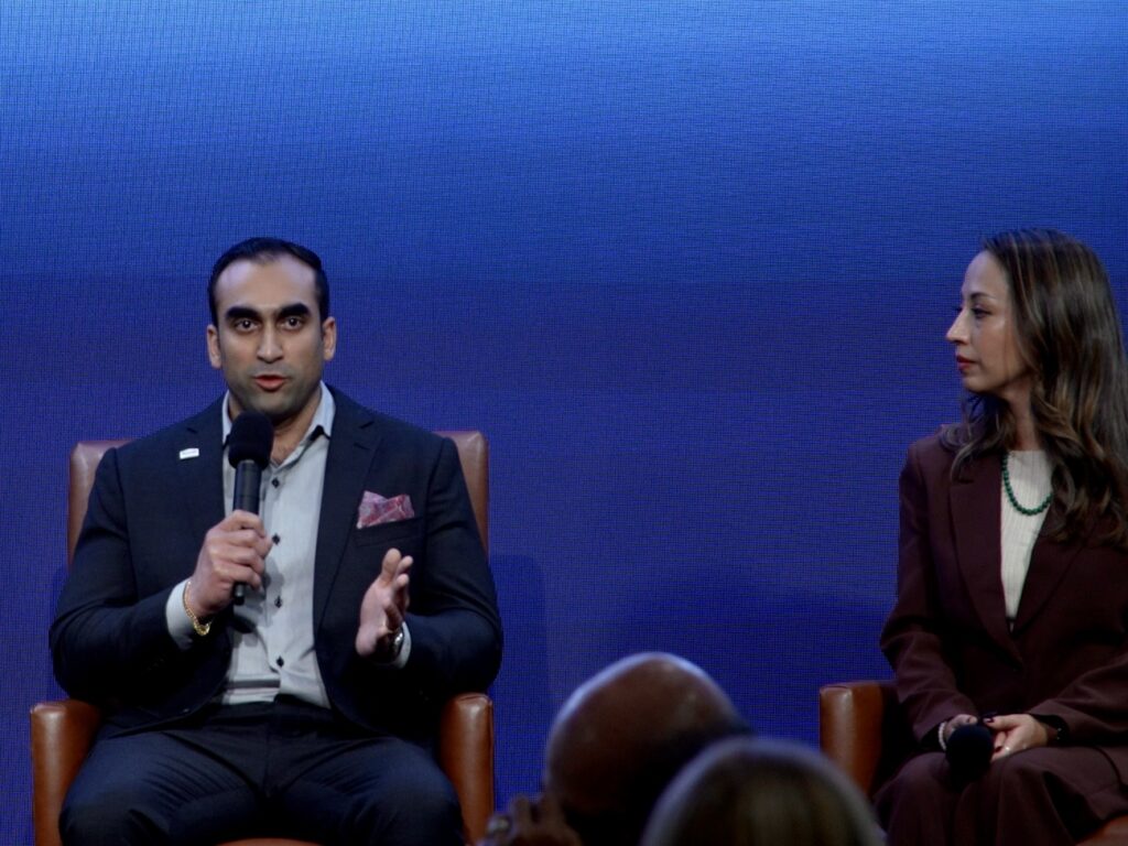 Shant Samtani, executive vice president of sales for Rhodes Enterprises, speaks into a handheld microphone while seated on stage during the Rio Grande Valley Business Journal’s 2026 Economic Outlook event as another panelist listens beside him.
