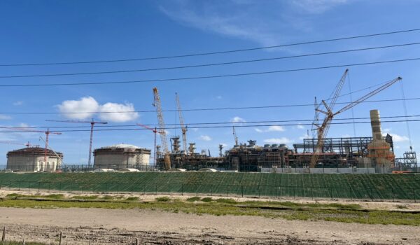 Cranes and industrial structures rise over large storage tanks and processing units under construction at the Rio Grande LNG site along the Brownsville Ship Channel.