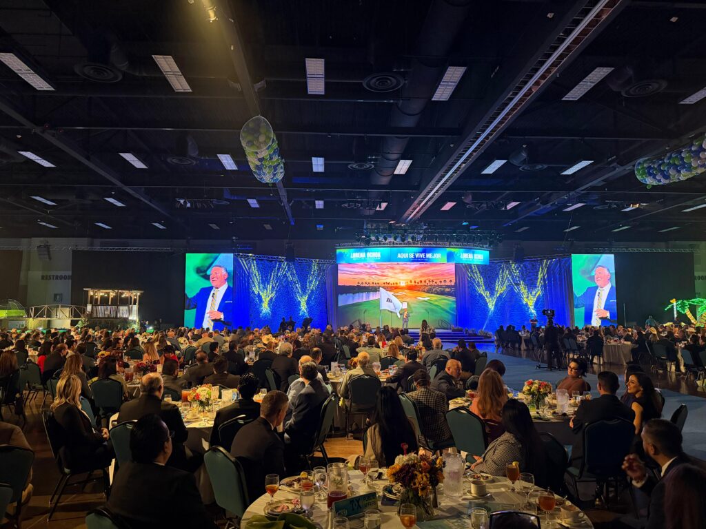 A wide view inside the McAllen Convention Center shows more than 1,300 attendees seated at round banquet tables facing a large stage during the McAllen State of the City address, with large projection screens and blue stage lighting.