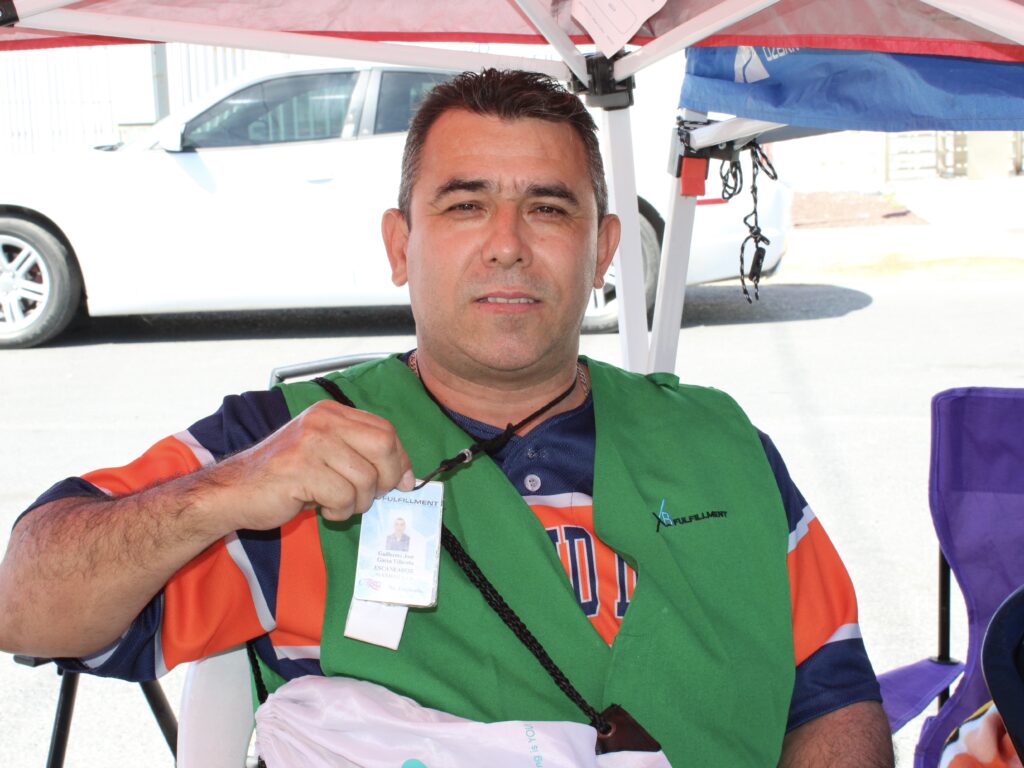 Man holds an ID badge while seated outside a warehouse facility following a shutdown.