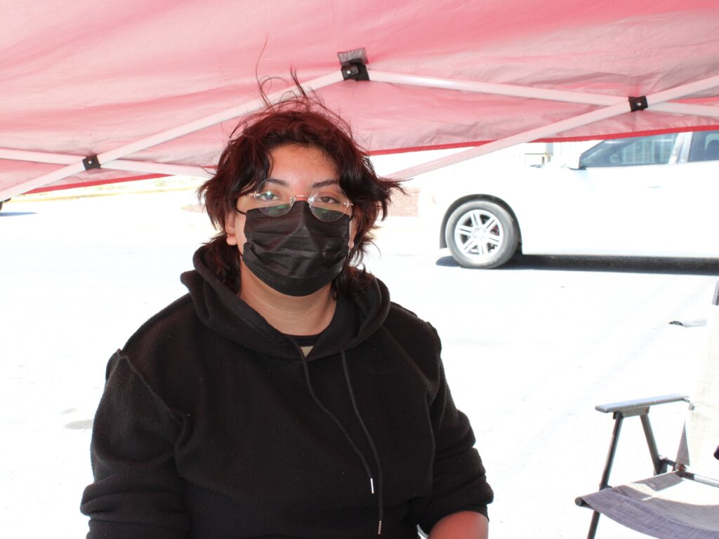 Former employee sits under a canopy during an interview outside a closed logistics facility.
