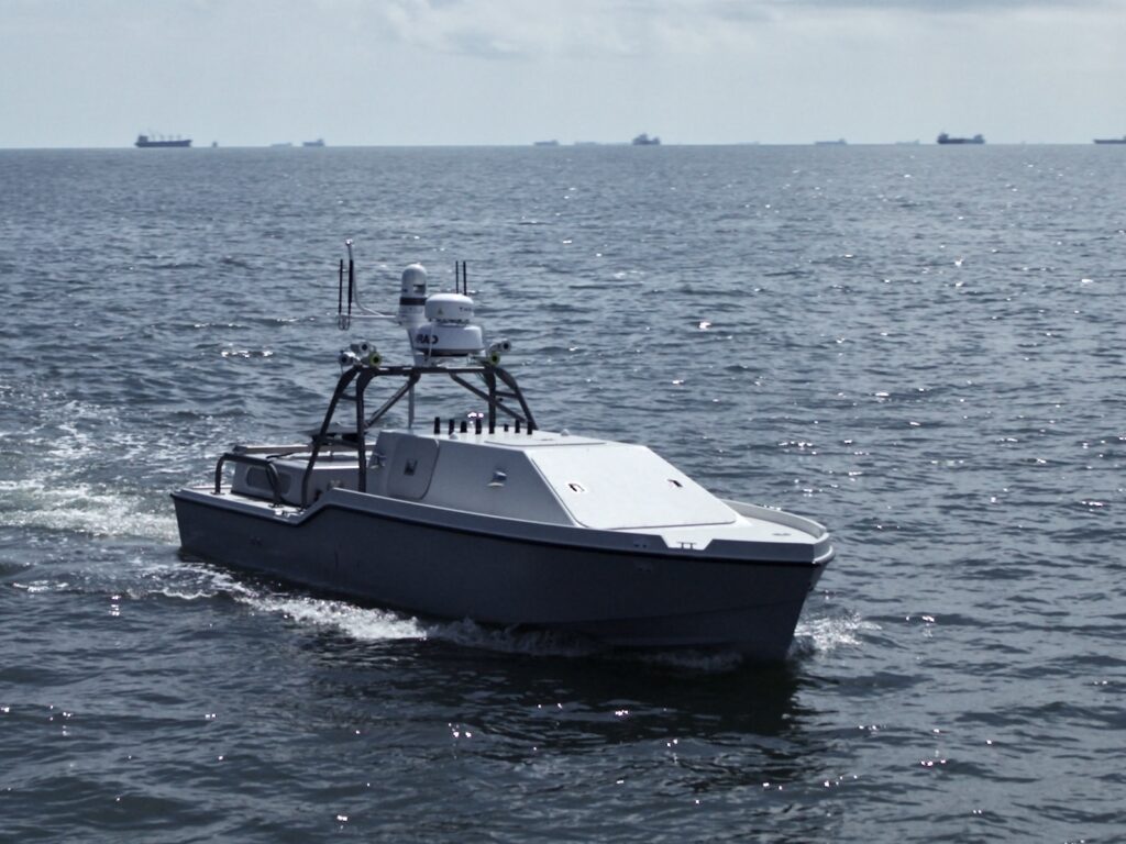 A Corsair autonomous surface vessel built by Saronic Technologies travels across open water with radar and sensor equipment mounted above the hull.
