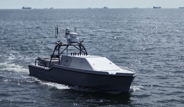 A Corsair autonomous surface vessel built by Saronic Technologies travels across open water with radar and sensor equipment mounted above the hull.