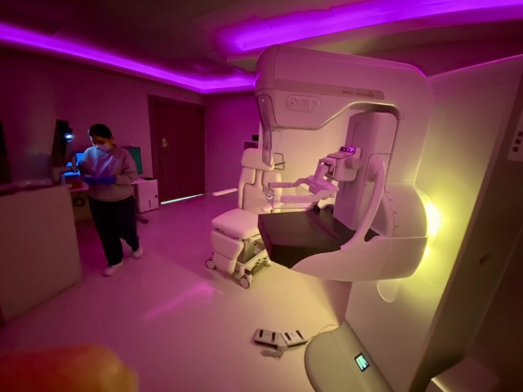 Un equipo de tomosíntesis mamaria en una sala de radiología con poca luz.