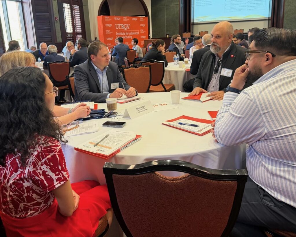 ttendees seated around a table discussing manufacturing topics during a UTRGV symposium in Brownsville.