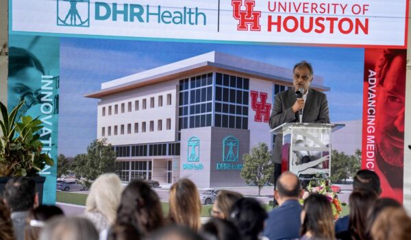 Dr. Manish Singh speaking at a podium during the groundbreaking of a DHR Health and University of Houston medical research and education center.