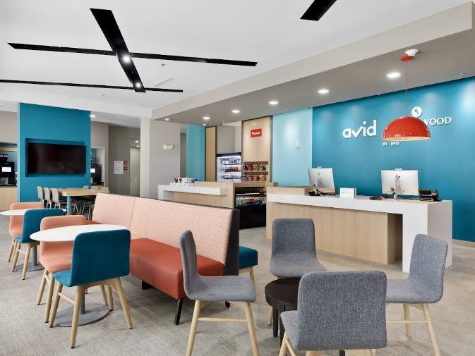 Vestíbulo moderno de un hotel con zona de descanso, recepción y zona de comedor en el interior del Avid Hotel, en Mission.