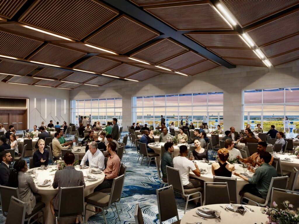 Representación del interior del salón de baile de un centro de convenciones, con mesas redondas, invitados sentados, grandes ventanales con vistas al mar y un techo revestido de madera con iluminación moderna.