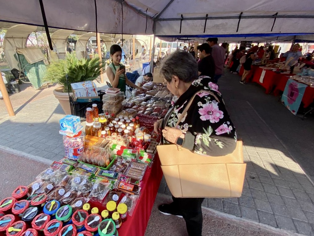 Una persona que está echando un vistazo a los artículos de una mesa de un vendedor ambulante en la Plaza Principal, donde se exponen productos artesanales.