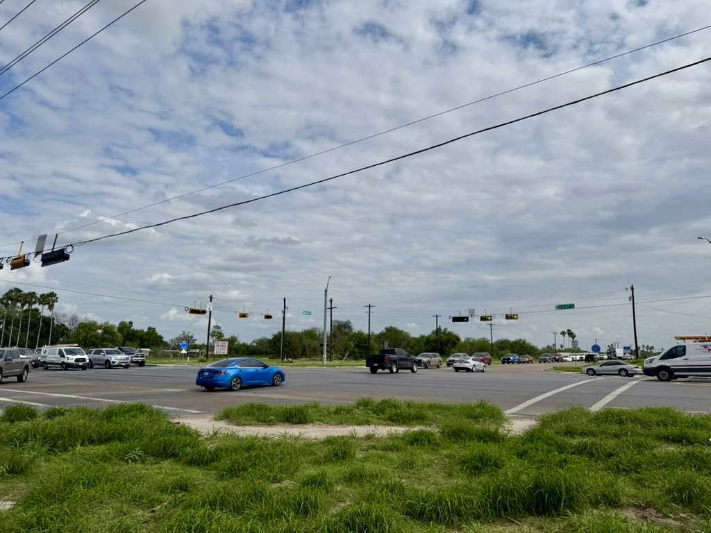Cruce de carreteras muy transitado, con coches y semáforos, cerca de una zona de desarrollo comercial en McAllen.