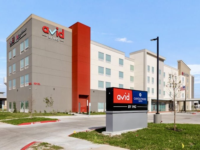 Exterior del edificio del Avid Hotel y Candlewood Suites en Mission, con los letreros de las marcas y la zona de aparcamiento.