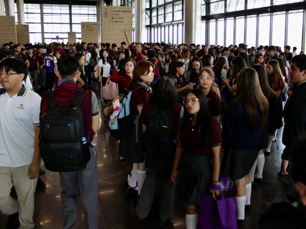 A large crowd of high school students gathers inside a convention center during an education expo in Reynosa.