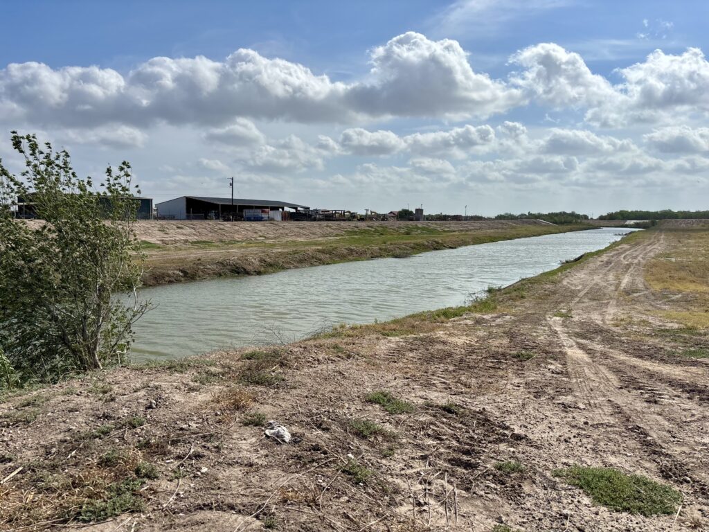 Wide drainage canal in Hidalgo County showing expanded banks and increased capacity to manage stormwater runoff.