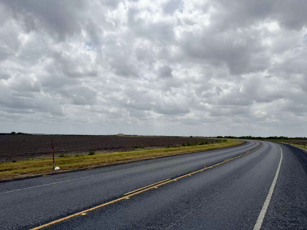 A rural road curves alongside open farmland near Harlingen where a data center is proposed.