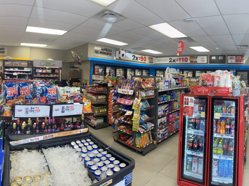 Shelves stocked with snacks, drinks, and convenience items inside an OXXO store.