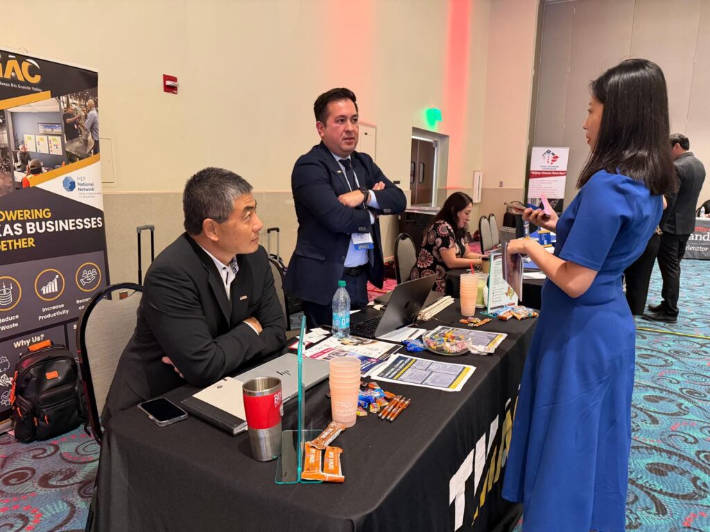 wo men at an exhibitor booth speak with an attendee during the Texas Governor’s Small Business Summit in Mission.