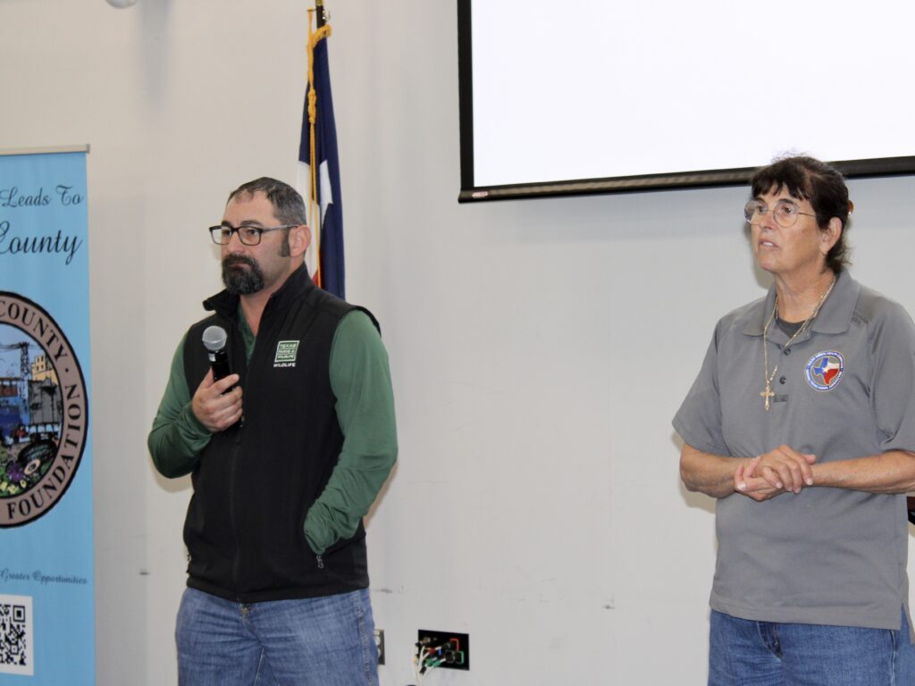 Eric Garza speaks into a microphone while Dr. Sandra Leyendecker stands beside him during a New World screwworm forum.