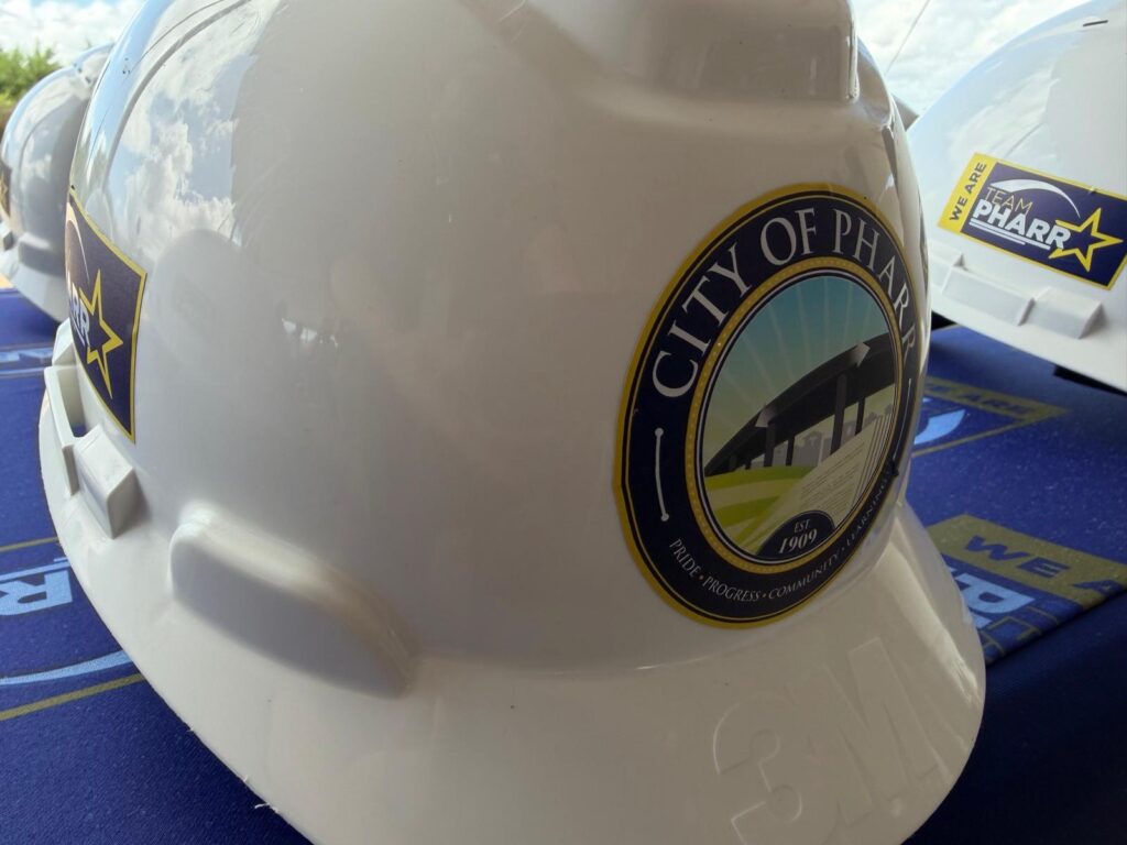 Close-up of a white construction hard hat featuring the City of Pharr logo at the groundbreaking ceremony for the new multi-purpose facility.
