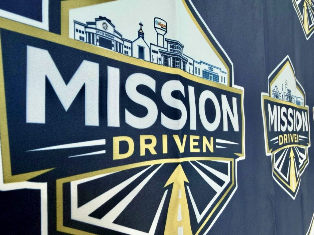 A close-up of the City of Mission’s “Mission Driven” logo displayed on an event backdrop.