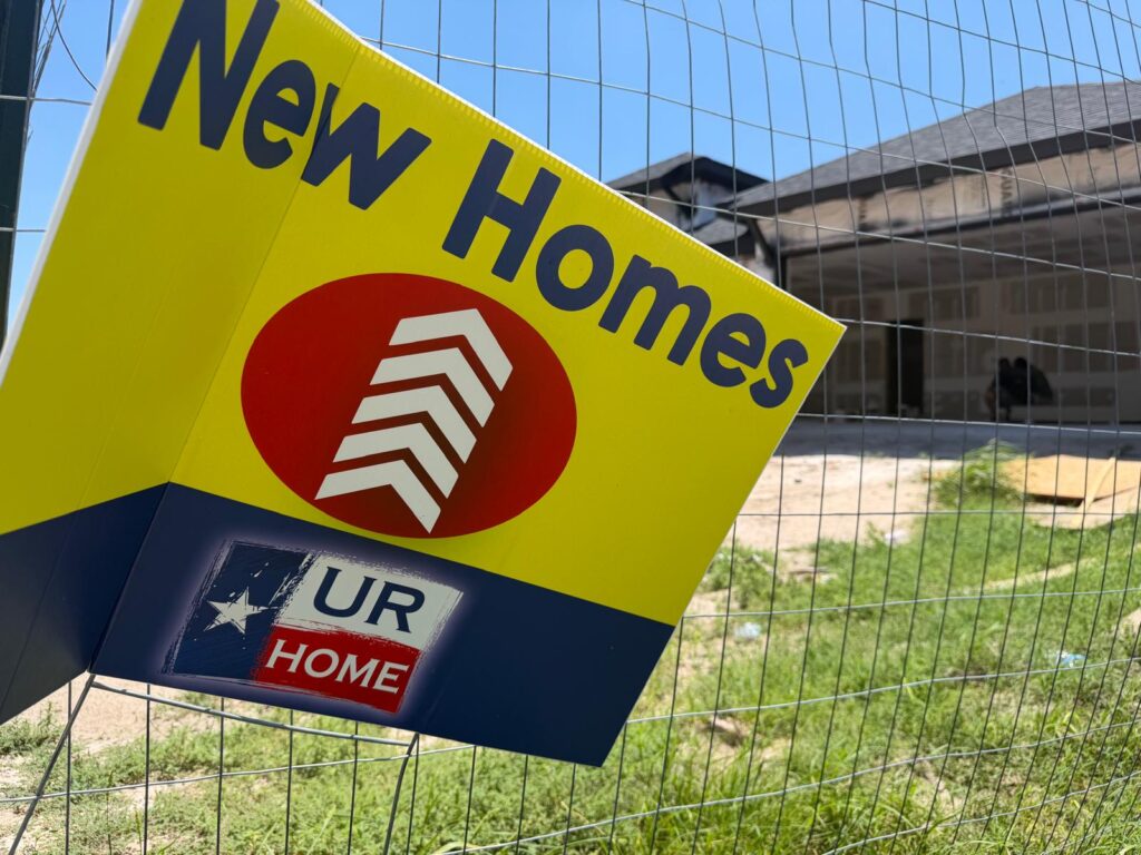 Un cartel que dice «Viviendas nuevas» se alza frente a una casa de nueva construcción que aún está en obras en una urbanización de McAllen.